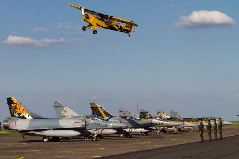 A Piper Cub in the NTM2011 theme colors flies over the flightline during the opening ceremony (photo by David Goovaerts)